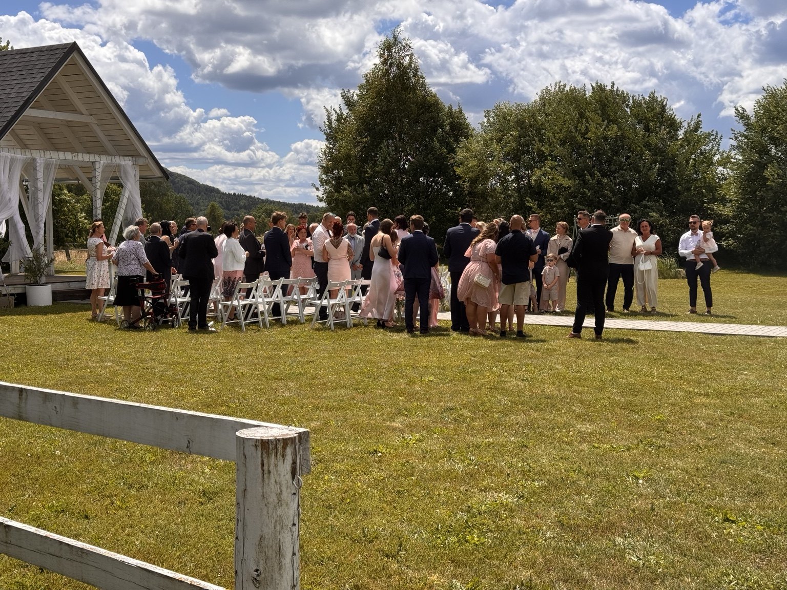 Svatební hosté u obřadu venku na louce